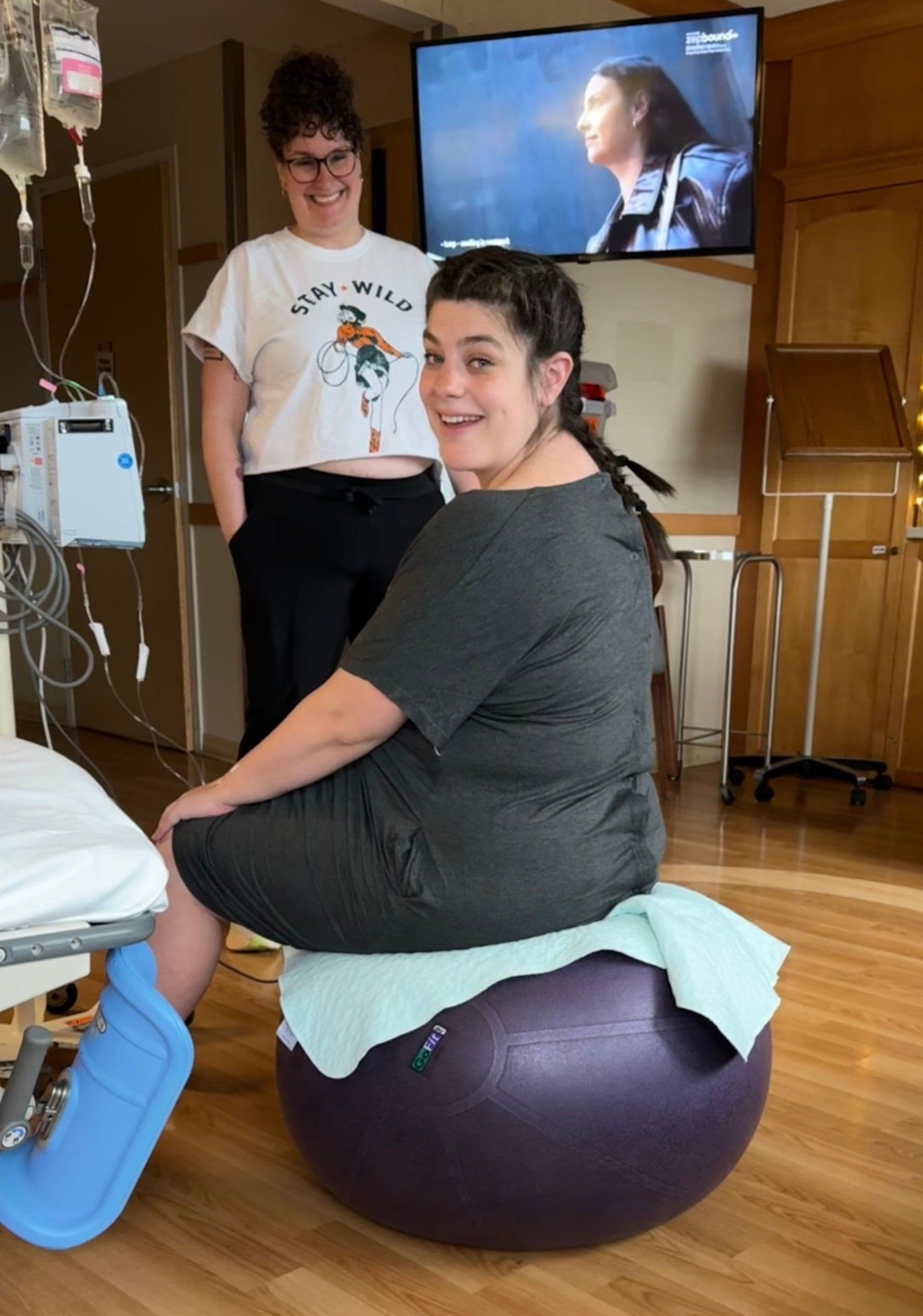 A laboring person smiling and laughing with their doula and partner in a birth space