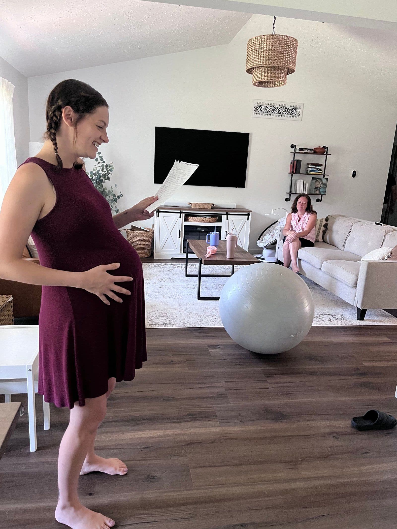 A pregnant client reads through her notes during a home prenatal visit while her Marigold doula looks on, a birth ball nearby